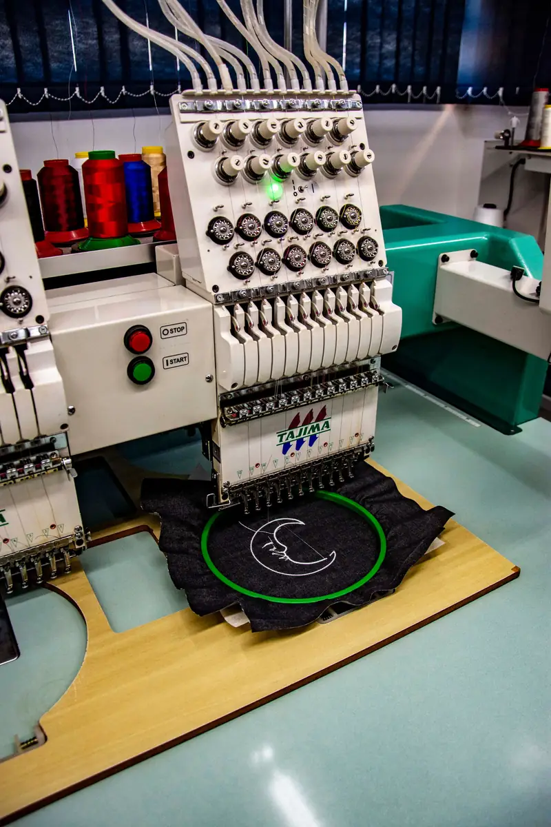 Embroidery machine stitching a logo onto a black garment