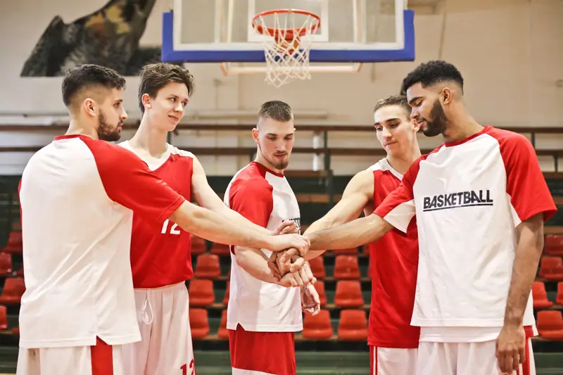 Basketball team in sublimated kits putting their hands in